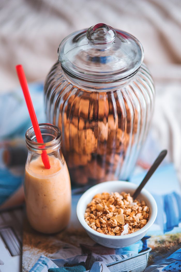 about-01 Delicious breakfast setup featuring granola in a bowl with a smoothie in a glass bottle.