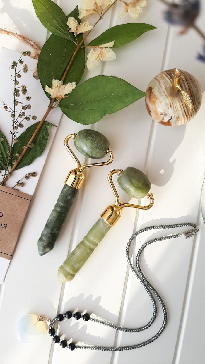 why-choose-us Flat lay of jade rollers, necklace, and leaves on a white surface, highlighting natural beauty and wellness.