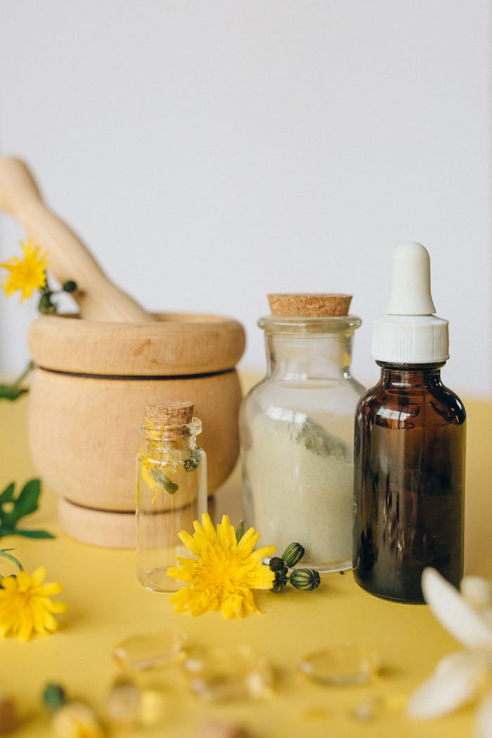 gallery-1 A still life of herbal medicine tools including mortar, dropper, and vials with flowers.